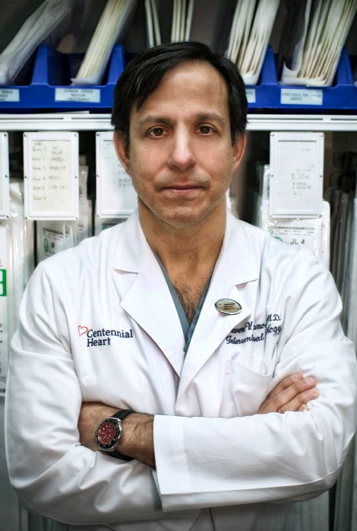doctor Steven Manoukian M.D. in a lab coat standing near a medical supply shelf of medical supplies