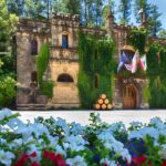the Chateau Montelena winery stone castle with white purple, and red flowers in Napa Valley