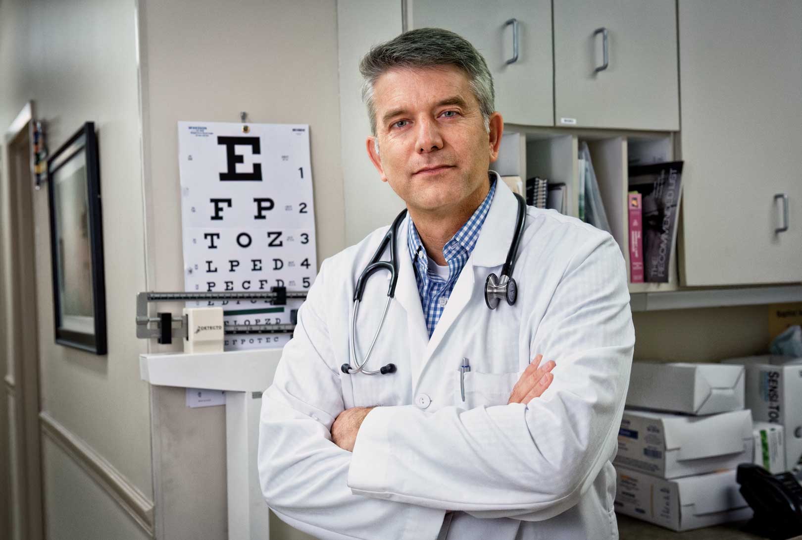 Dr. Parker Panovec wearing a lab coat standing in a clinic next to an eye chart