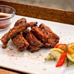 BBQ dry rub ribs on a plate with garnished peppers by Chef Shane Autry