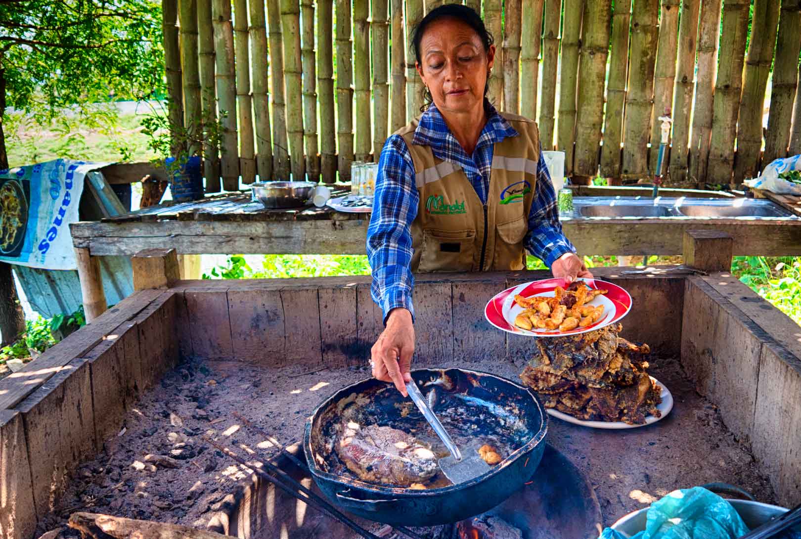 woman cooking on grill plantains, fish roe, and freshly caught fish in Sendero los Caimanes Ecuador