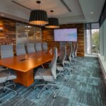 conference room with wooden plank walls gray carpet wood conference table gray chairs and lights