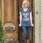 Kellie Pickler Wearing blue United We Stand USO T-Shirt standing at a large wooden front door