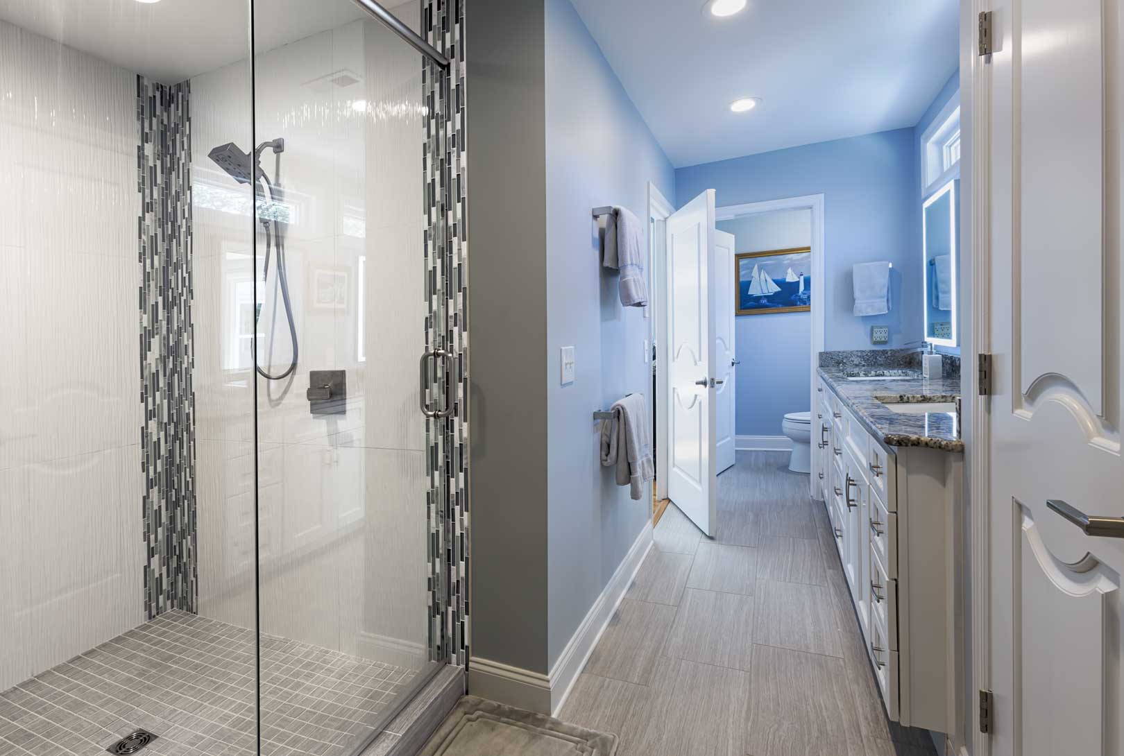 A remodeled master bathroom with blue gray walls, and gray and white tile at a home