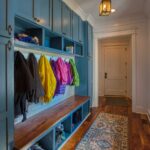 A mudroom with blue-gray colored cabinets and shoe and jacket storage at the side entryway door