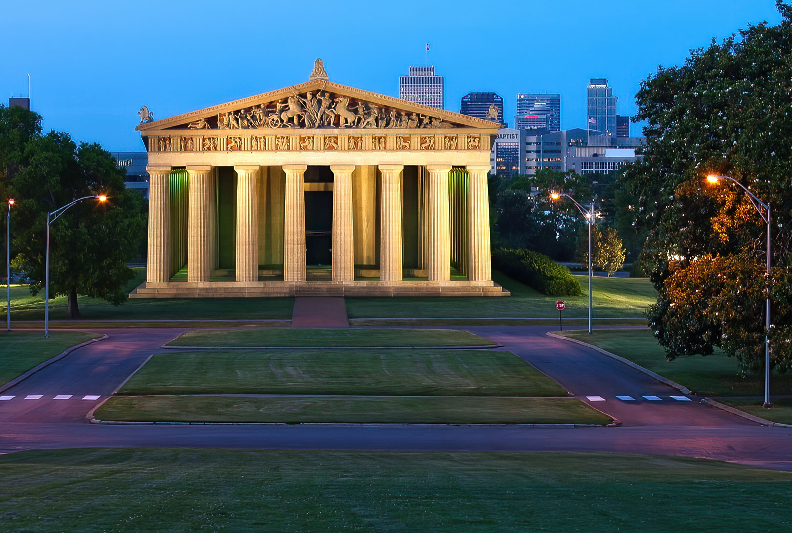 The Parthenon at Centennial Park at sunrise with lights on and downtown in the distance