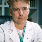Rand Paul sitting in his office wearing a white laboratory coat