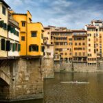 The Ponte Vecchio bridge crossing over the Arno River with 2 man kayak in distance Florence Italy