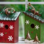 two holiday snowflake-painted birdhouses one in red and one in green with tin roofs
