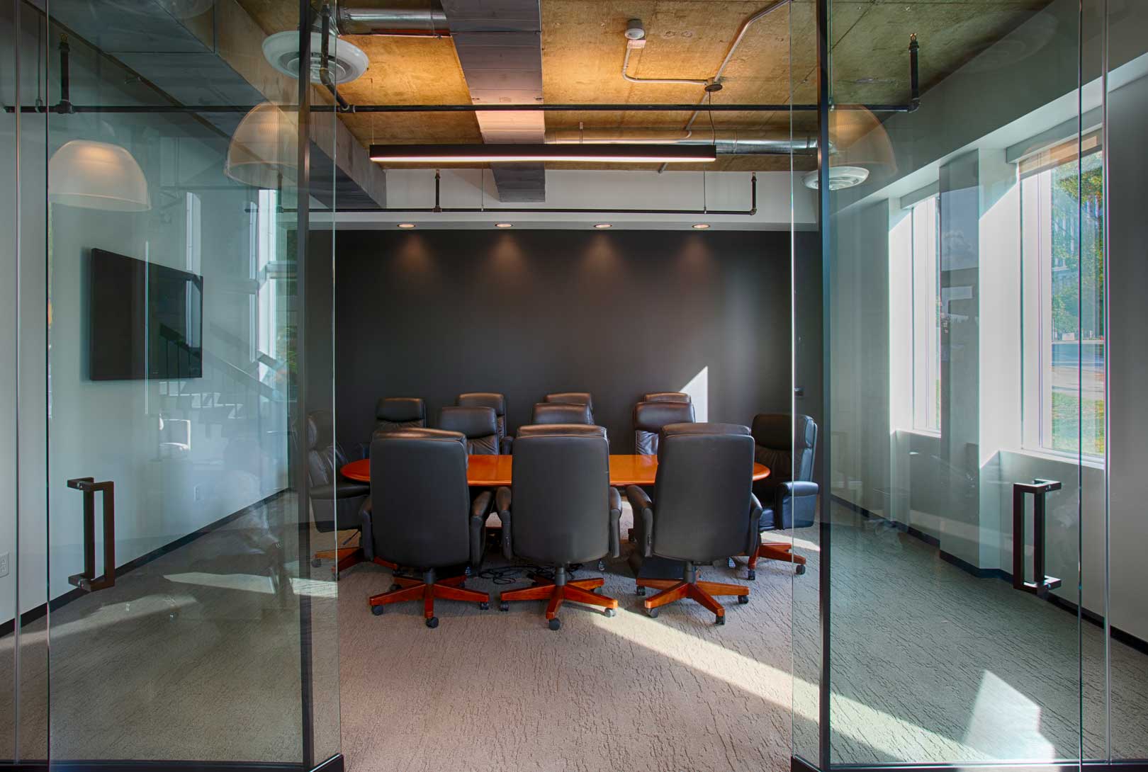 industrial designed conference room with concrete ceiling, glass entrance, painted white and gray with wood table