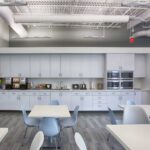 modern employee kitchen cafe with white counters, tables, and chairs