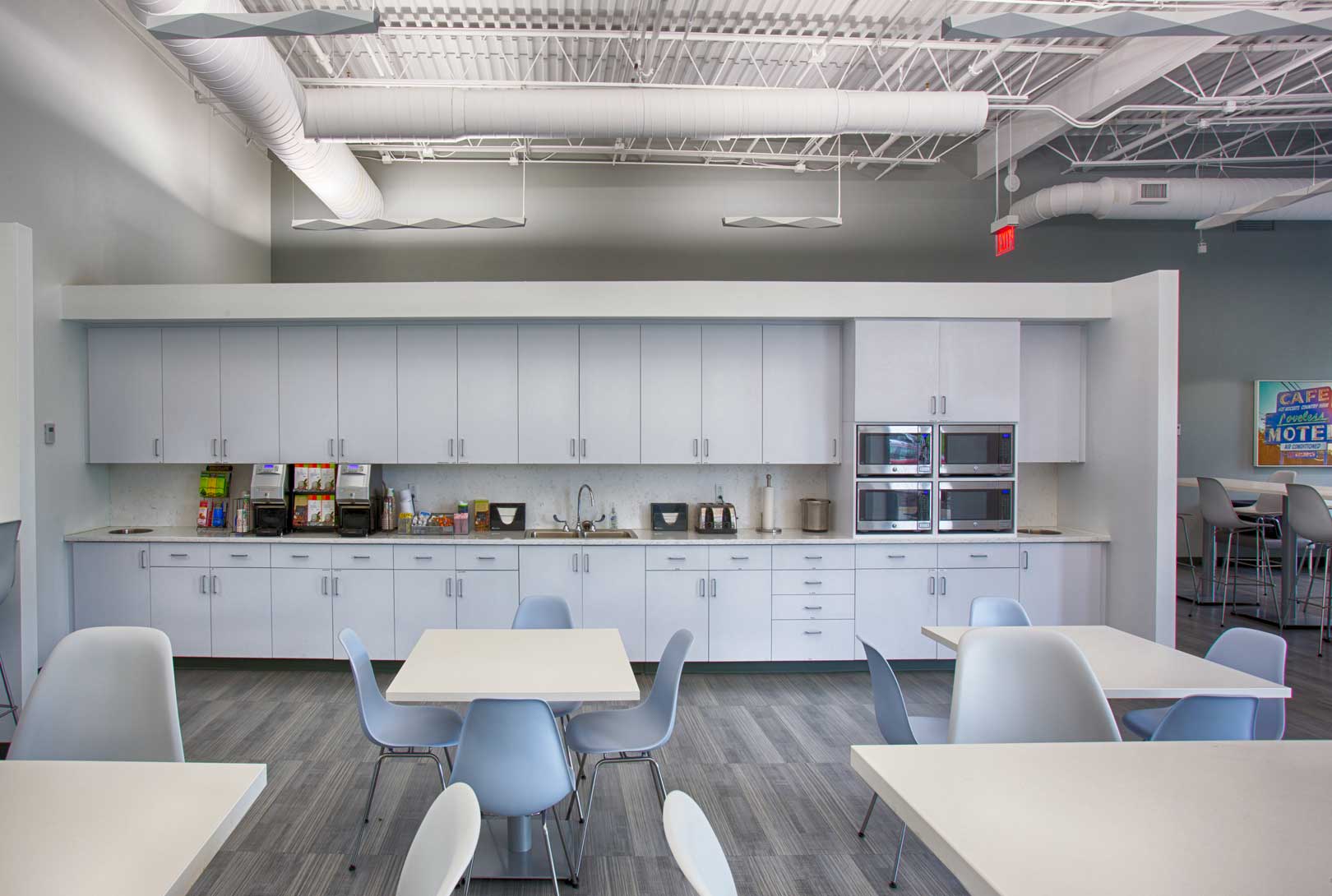 modern employee kitchen cafe with white counters, tables, and chairs