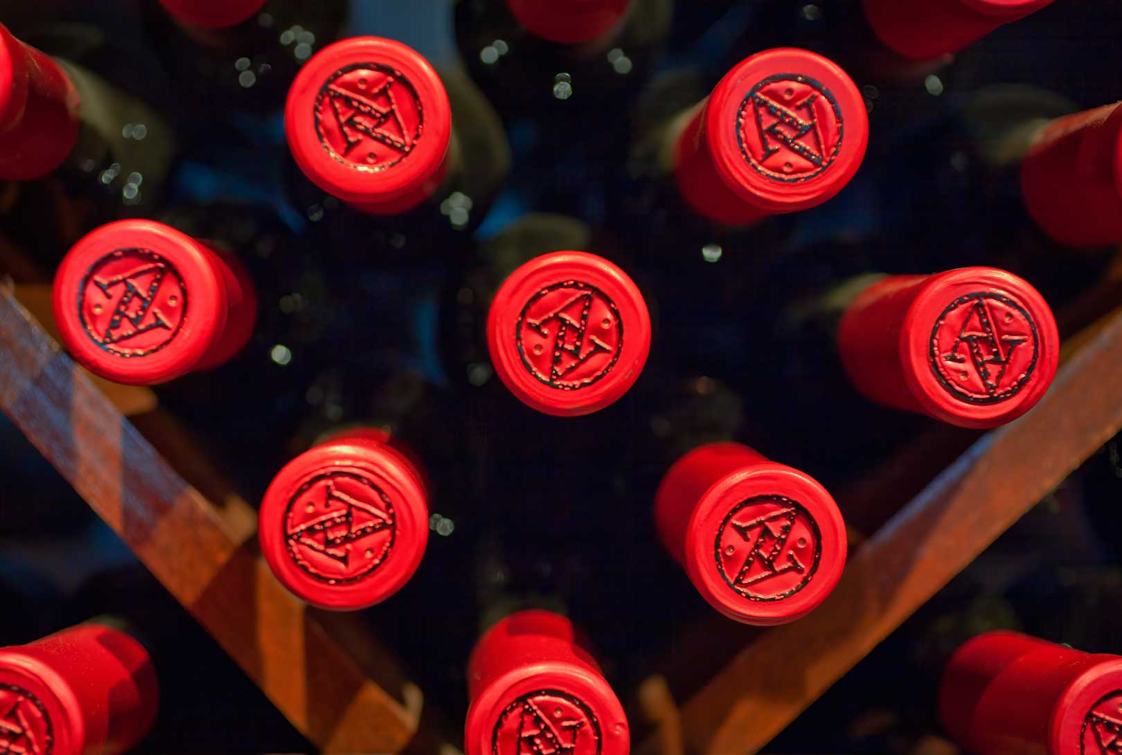 wine bottles with red tops stacked on a wine rack