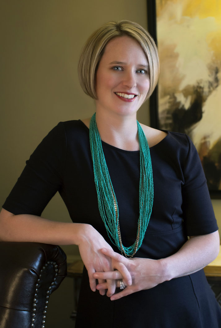 environmental business headshot of Baylor Bone Windell in black dress with green scarf in her office