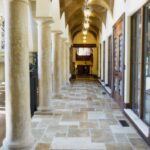 Mediterranean-style corridor of pillars with marble tile and wood accents