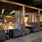 a breakroom with warm wood-toned booths, lights, and tables