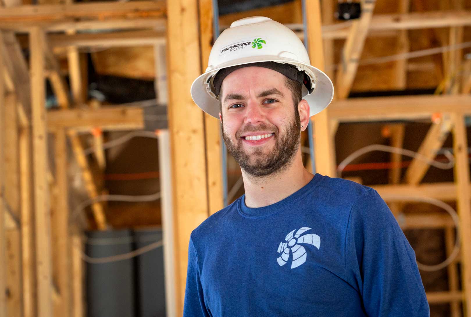 white male with beard in white hard hat and blue shirt in home under construction