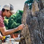 a concrete worker staining a fabricated concrete tree by hand with brush
