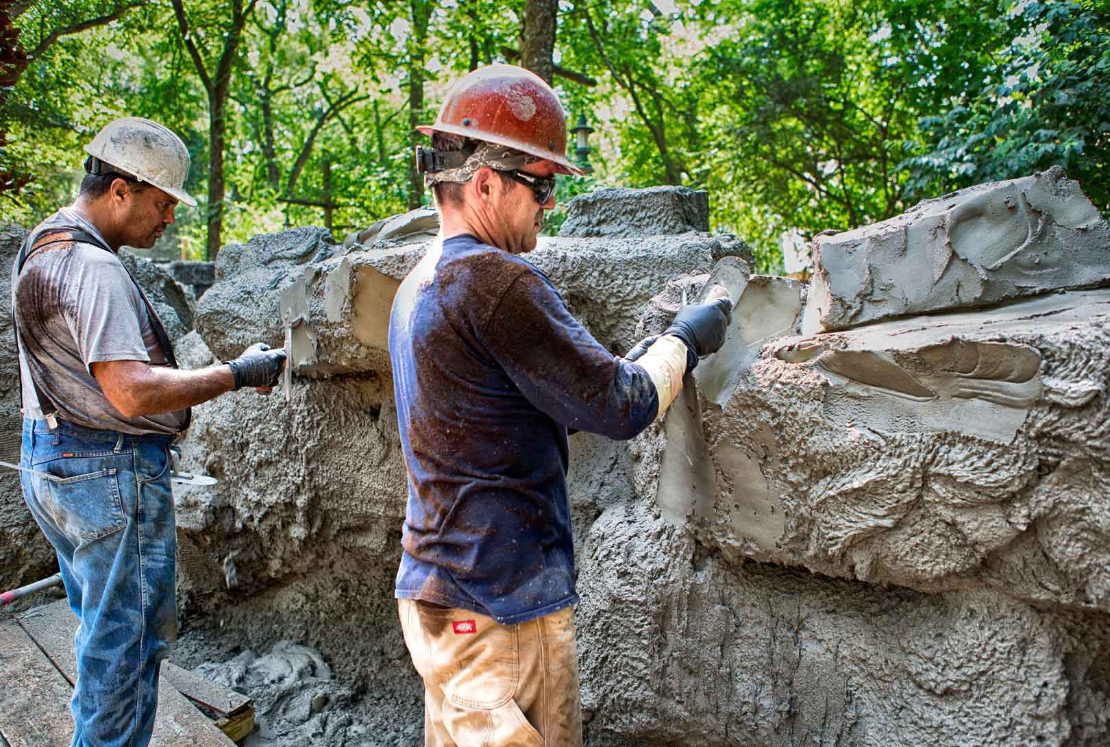 Concrete Fabricators Troweling Concrete Into A Rock Wall