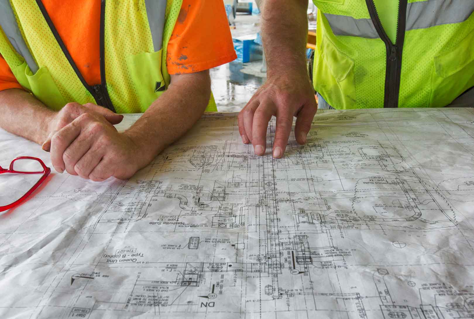 hands of two construction workers with the blueprints