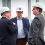 three male executives in hard hats at rooftop hotel construction site