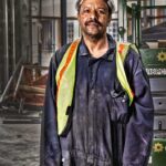 african american male construction worker with a mustache in blue overalls at construction site