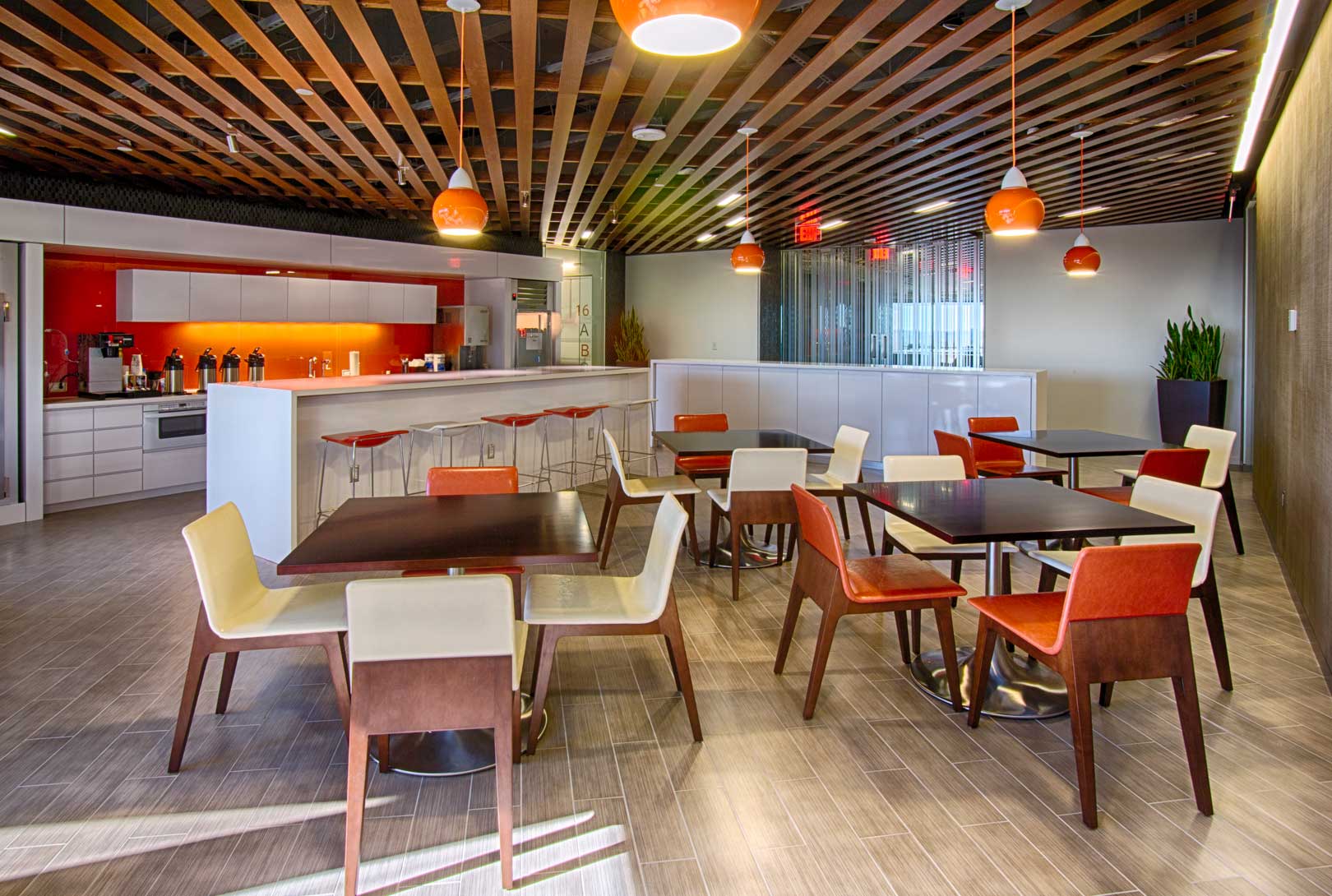 modern designed employee kitchen and break room space with accents of wood, and orange and white colors