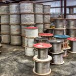 large wooden spools with steel cable structural wire rope are stacked in a warehouse.
