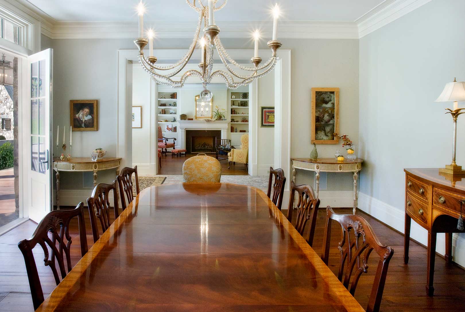formal dining room with an antique dining room table, chandelier, and fireplace in the distant foyer