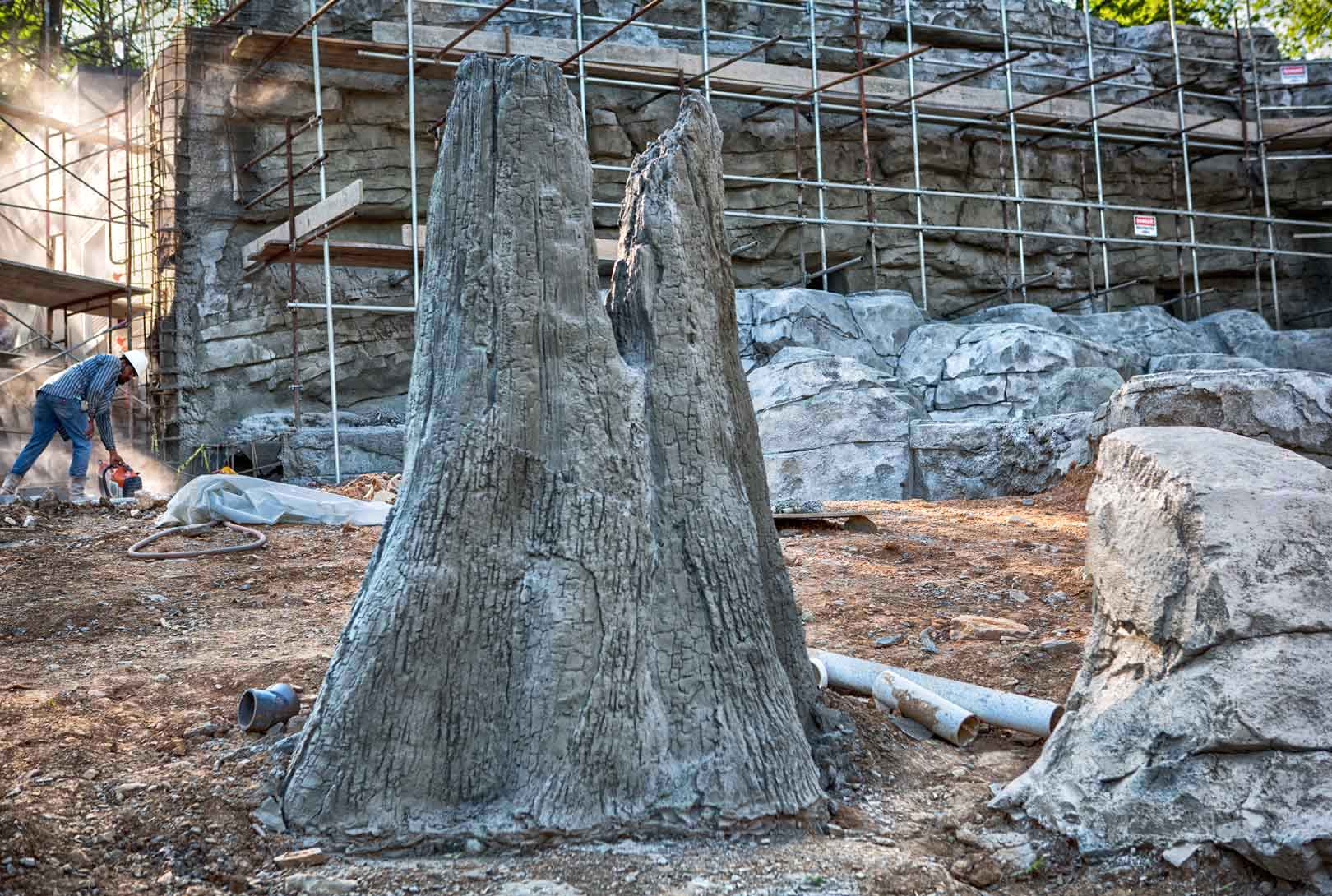 concrete fabricated tree stump with other rock boulder formations under construction