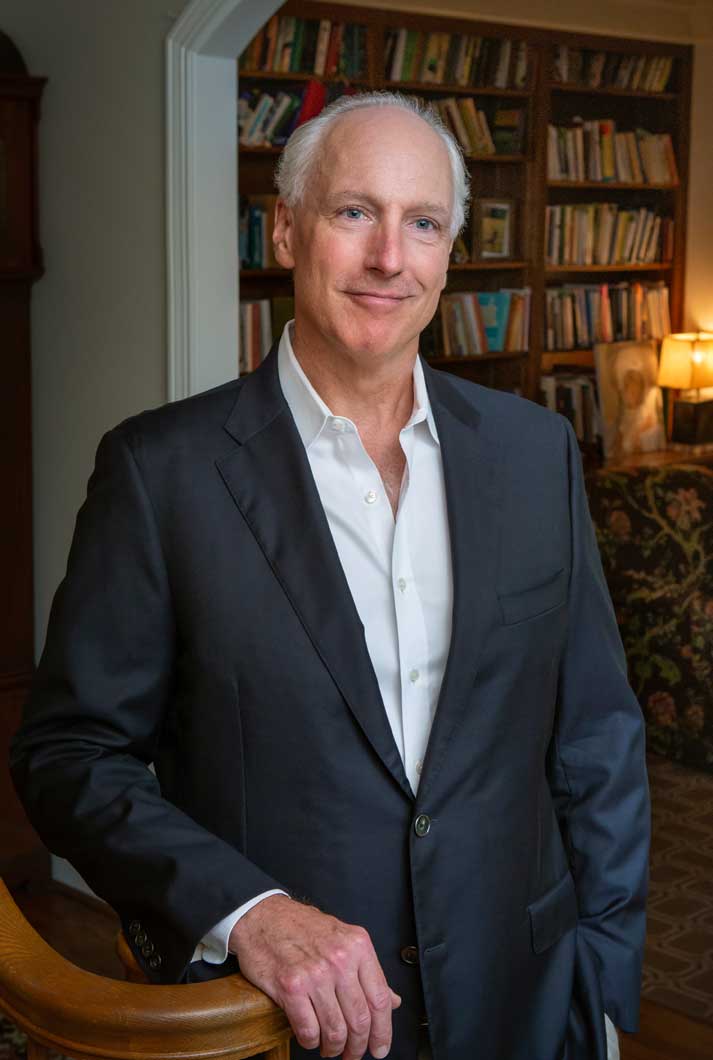 environmental corporate headshot of Richard Kennelly wearing a suit jacket near his study in his home
