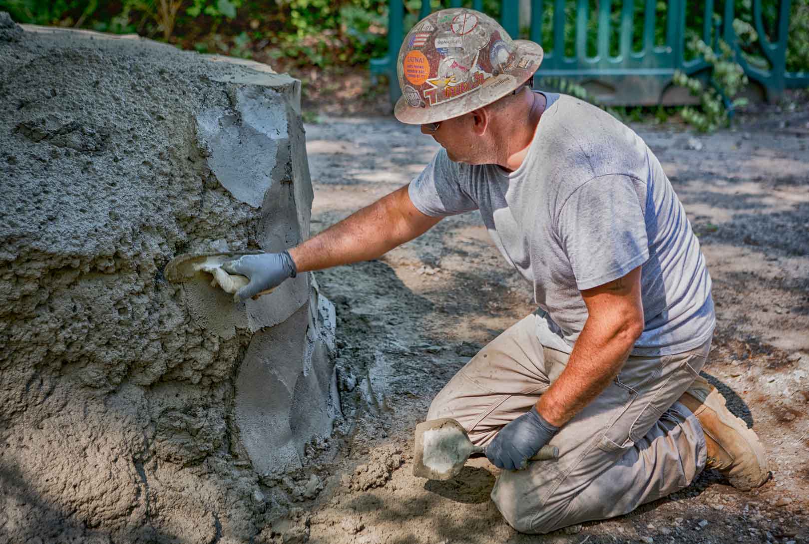 concrete worker in gray with hardhat spreading concrete with a trowel