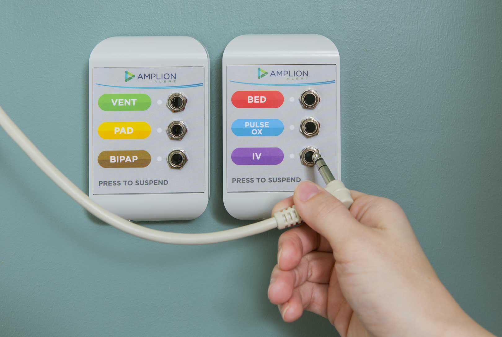 A hand demo holding a connector with two Amplion Alert medical suspend hospital panels