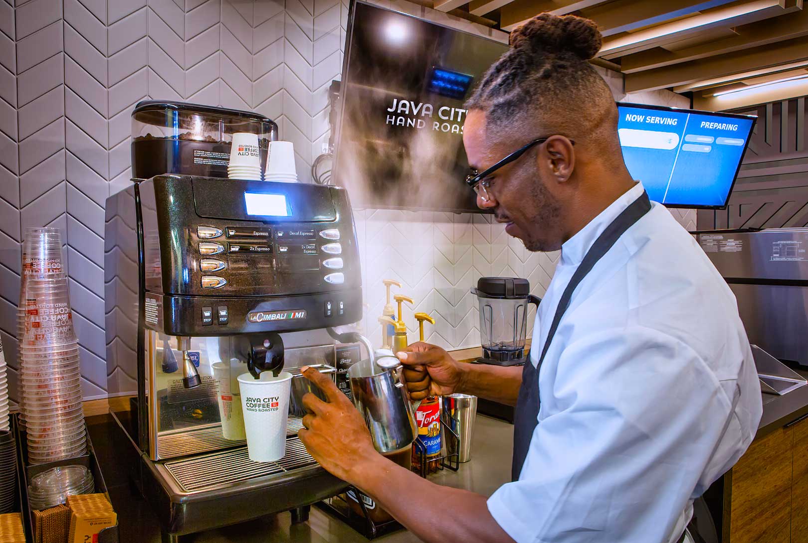 A Man Frothing Milk At A Cappuccino Machine In An Aramark Micro Market