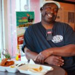 Bolton Mathews sitting at table in restaurant with hot chicken and bread dinner