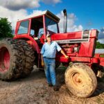 Hank Delvin Sr. standing next to his red International 1066 tractor on his farm