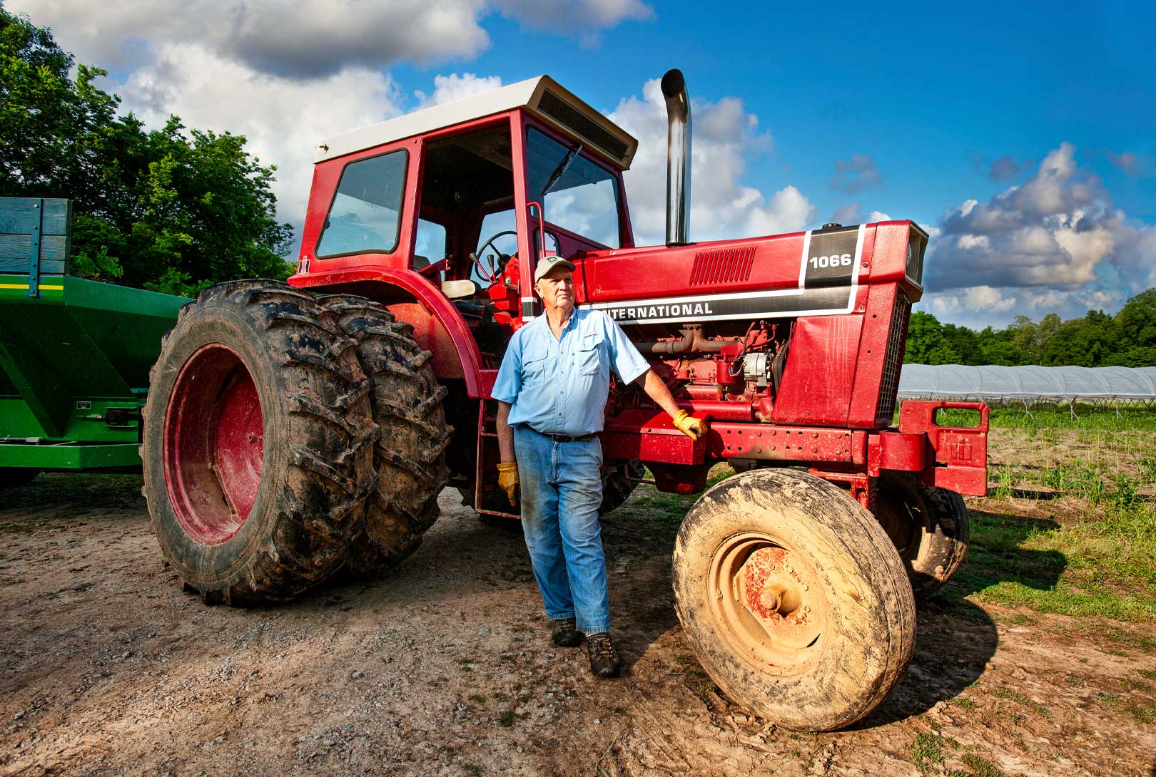Hank Delvin Sr. standing next to his red International 1066 tractor on his farm