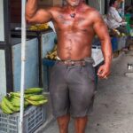 Ecuadorean man in shorts no shirt smiling flexing muscles in market in Bahia de Caraquez Ecuador