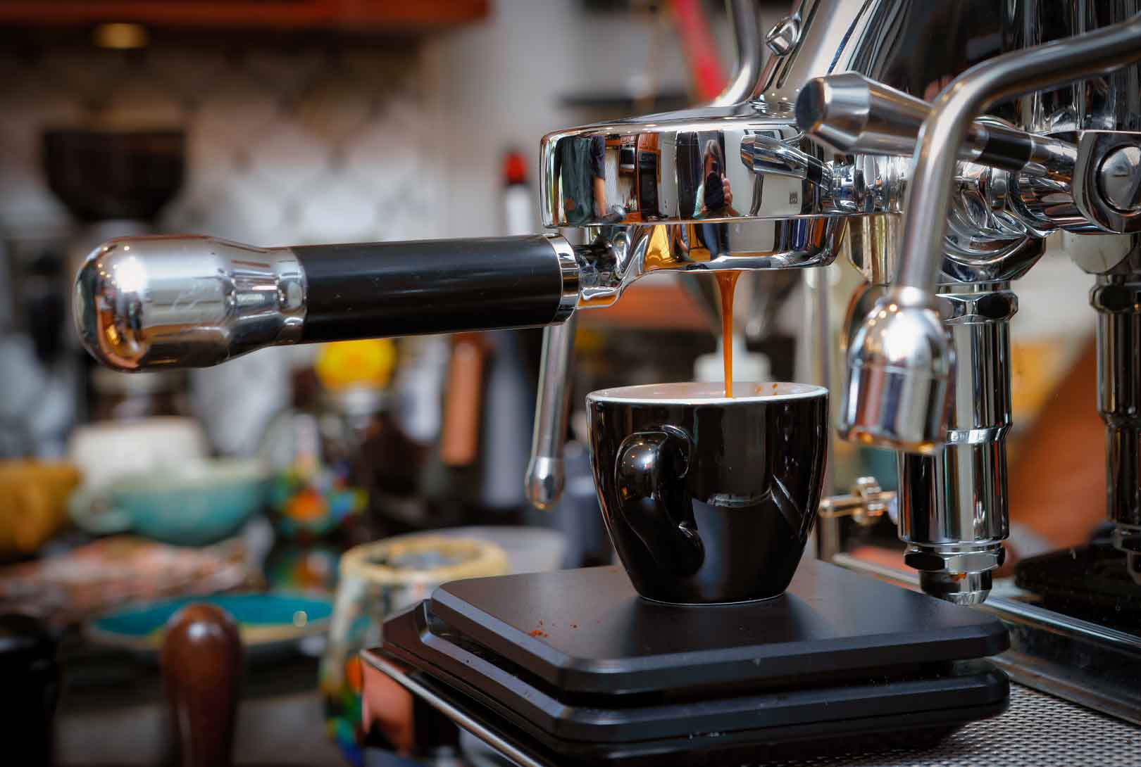 A commercial-grade expresso machine making expresso as it drips into a black cup in a home kitchen
