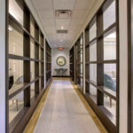 office space corridor with carpet leading to table and mirror with wood-trimmed glass