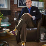 executive Stryker Warren in his Nashville loft sitting in a chair in his living room wearing a suit