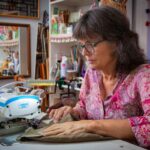 Twyla Lambart sitting at her sewing machine working in her home studio