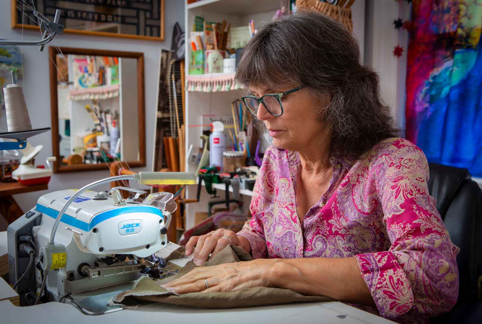 Twyla Lambart sitting at her sewing machine working in her home studio