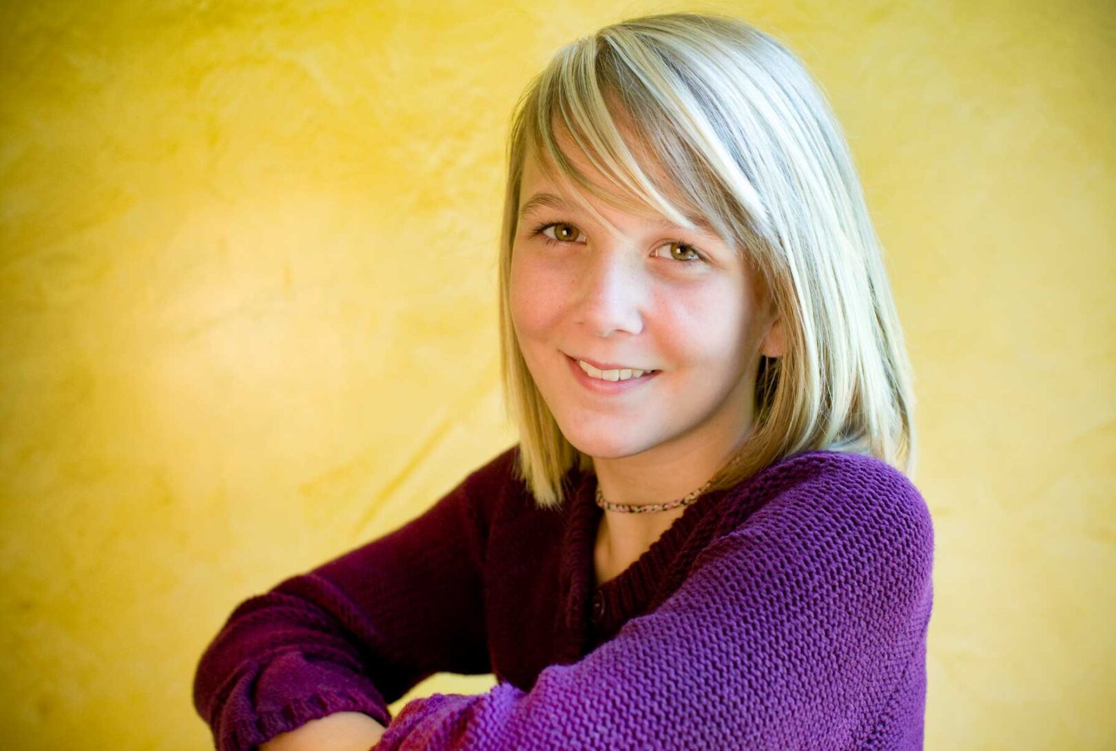 A young girl in a purple sweater posing for a photo.