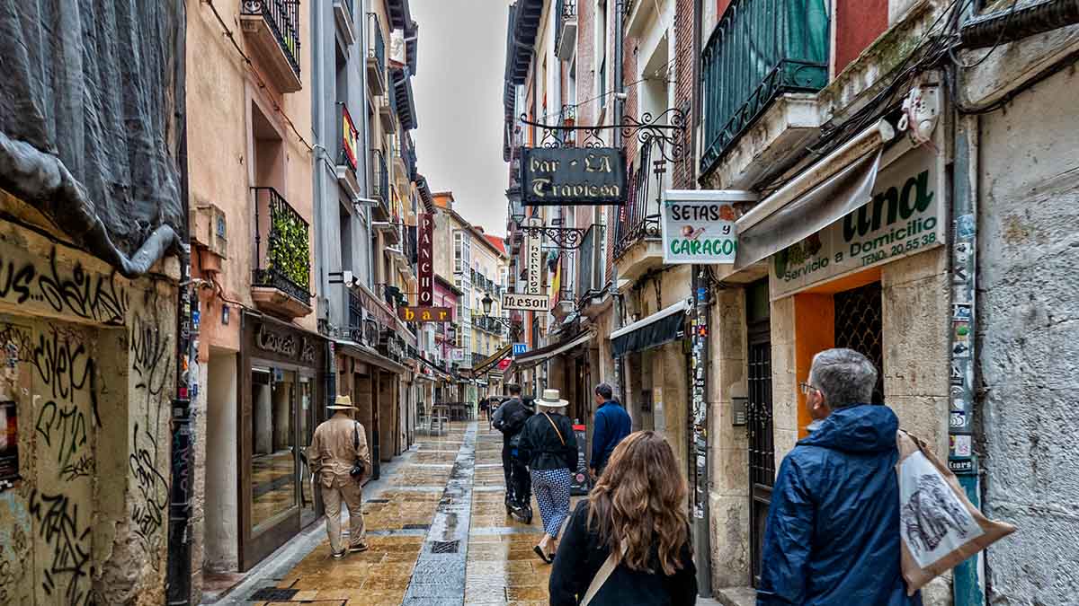 Shoppers walking in the rain along the wet streets of Burgos, Spain.