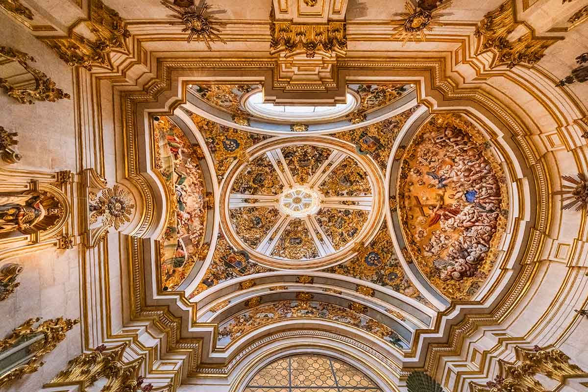 The ornate, golden-domed ceiling of the Burgos Cathedral features detailed frescoes and symmetrical architectural designs in Spain.