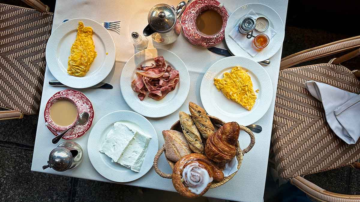 A table set for breakfast with omelets, sliced ham, cheese, assorted breads and pastries, cups of coffee, and small jars of jam at the Hotel Landa restaurant in Burgos, Spain.
