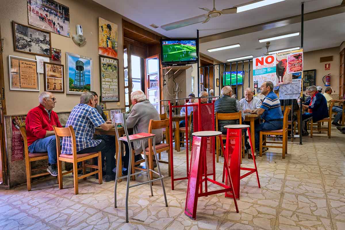 A small cafe in Lerma, Spain, with men playing cards while watching soccer.